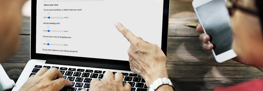 People looking at a computer screen. It has a section of a health questionnaire on it. This section is about you nose. The people are pointing at the screen. We are looking over their should so we can't see their faces.